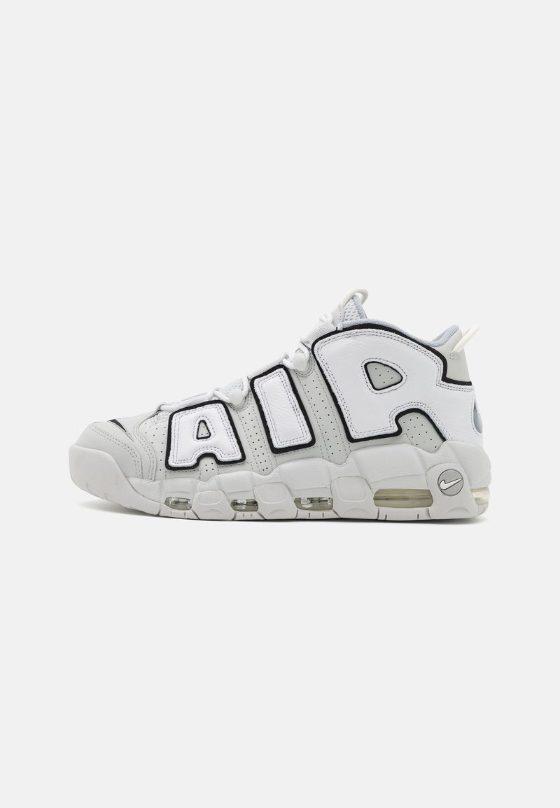 Witte sportieve sneakers met grote zwarte "AIR" letters. Bevatten mesh- en leermaterialen, gestructureerde accenten en zichtbare luchtkussens.