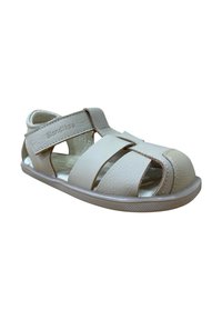 Sandalias beige hechas de cuero sintético texturizado; diseño abierto con correas entrelazadas, cierre ajustable de Velcro y suela de goma.
