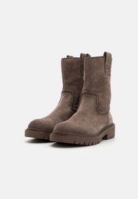 Brown suede ankle boots with a rounded toe, sturdy rubber sole, and stitched detailing. Features pull tabs on the sides for easy wear.
