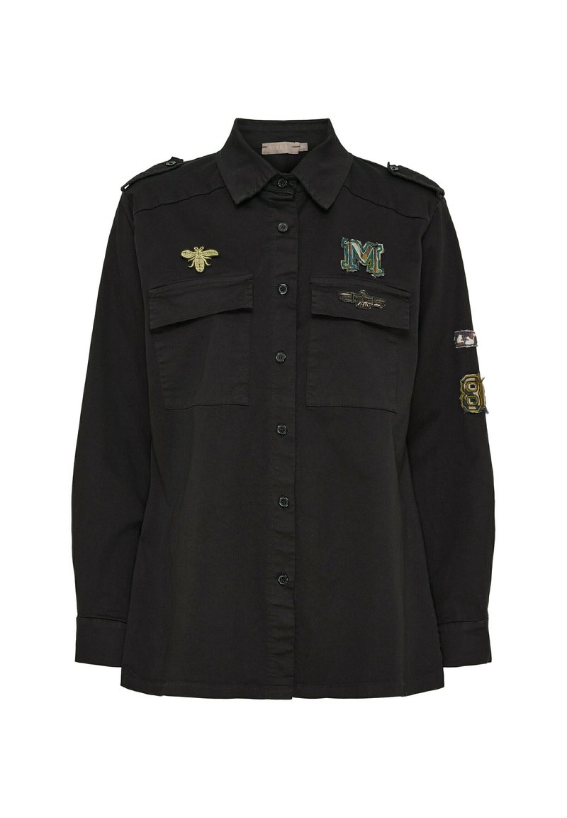 Svart skjorta med knappar har två bröstfickor, broderade bin och bokstaven 'M', samt axelremmar. Mjuk tyg, vanlig passform.