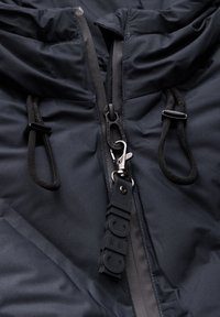 Veste isolante bleu foncé avec un col haut, fermeture éclair et cordons de serrage ajustables. Présente une étiquette en caoutchouc avec la marque "ICEGIL".