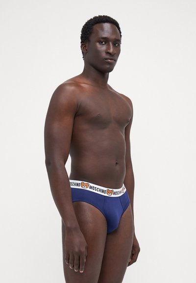 Navy blue brief underwear with a white waistband featuring a bear logo. Soft texture, fitted design, and minimalistic style.