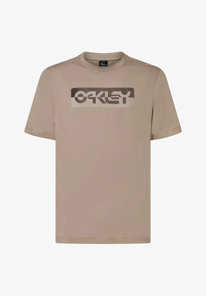 T-shirt beige à manches courtes Oakley avec un logo rectangulaire comportant des lignes ondulées et le nom de la marque sur la poitrine.