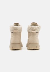 Beige ankelstøvler med faux fur krave, teksturert skinn, polstret innvendig, gripevennlig gummisåle og to trekkstropper bak for lettere påkledning.
