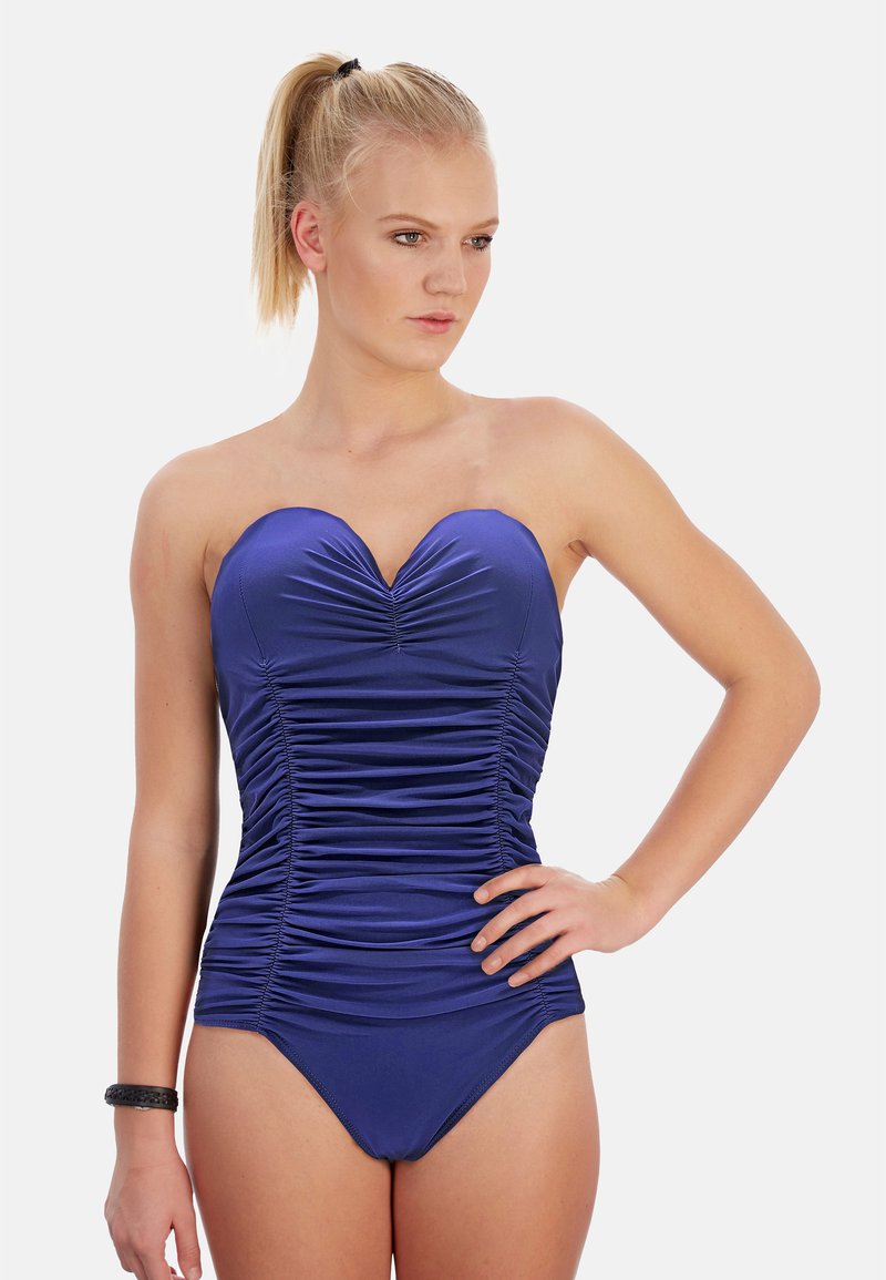 Maillot de bain sans bretelles de couleur bleu marine avec des détails plissés sur le buste et la taille, et un bas ajusté. Texture lisse et design épuré.