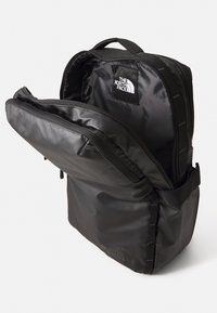 Svart ryggsäck i slitstark tyg, med en framträdande logotyp, dragkedjefack och en strukturerad form med justerbara axelremmar.