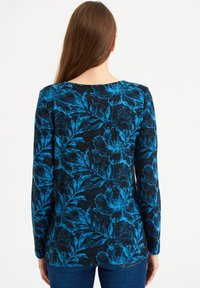 Top de manga larga negro con un vibrante patrón floral azul. Textura suave con cuello redondo y bajo curvado.