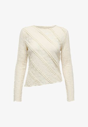 Kremowa bluzka z długim rękawem, wyróżniająca się teksturowanym materiałem z diagonalnymi wzorami z koronką oraz dekoltem w łódkę. Lekko asymetryczny krój u dołu.