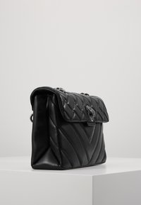 Borsa a tracolla in pelle nera con un design trapuntato, hardware in argento e chiusura a patta. Presenta una tracolla a catena e una forma strutturata.