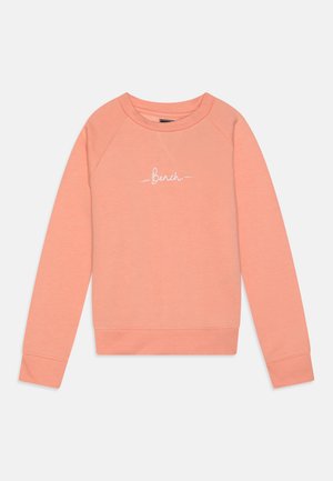 Sweatshirt couleur pêche avec un col rond, des poignets et un ourlet côtelés. Présente un logo "Bench" blanc sur le devant. Fabriqué en matériau doux.
