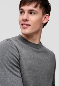 Pull en tricot gris avec un col rond, un col côtelé et des manches longues. Texture lisse et détails de couture réguliers. Design minimaliste.
