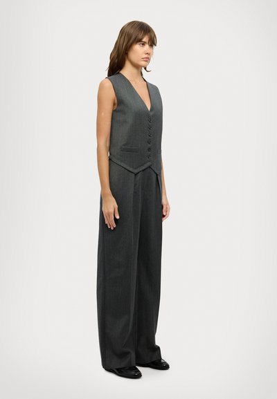 Gilet gris ajusté avec un décolleté en V profond, six boutons et deux poches avant, associé à un pantalon large en tissu assorti.