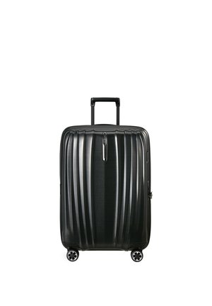 Valigia rigida nera con quattro ruote piroettanti e manico telescopico estratto, in piedi su sfondo bianco.