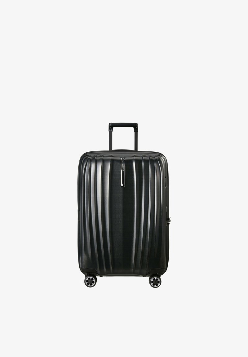 Valise rigide noire avec quatre roues pivotantes et une poignée télescopique déployée, debout sur un fond blanc.