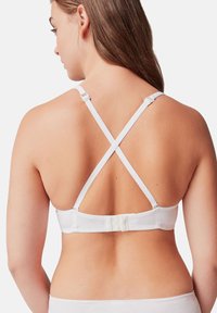 Soutien-gorge blanc avec un design à dos croisé. Bretelles ajustables et détail de fermeture à crochets. Texture lisse et style minimaliste.