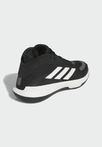 Zwarte sportieve schoen met een gestructureerde mesh bovenkant, wit drie-strepen ontwerp, slanke silhouette en een duurzame zwarte zool met witte accenten.