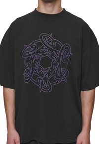 Black oversized t-shirt featuring a purple intertwined pattern in the center. Short sleeves and a crew neckline. Cotton material.