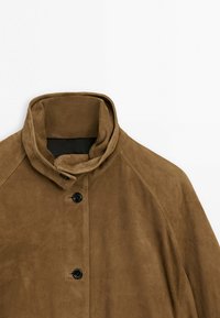 Giacca in camoscio marrone con collo alla coreana e chiusura frontale con bottoni neri su sfondo bianco.