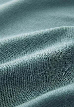 Țesătură texturată într-un teal moale și estompat. Prezintă nervuri subtile și pliere ondulate, evidențiind flexibilitatea și o suprafață moale.