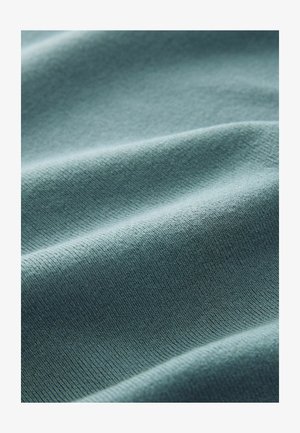 Teksturowana tkanina w miękkim, stonowanym odcieniu tealu. Charakteryzuje się subtelnym prążkowaniem i falującymi fałdami, które podkreślają elastyczność i miękką powierzchnię.