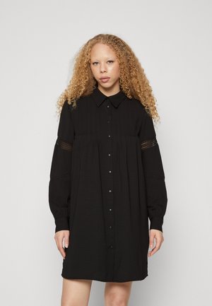 Black button-up dress made of textured fabric, featuring long sleeves, a collared neck, and lace detailing on the sleeves.