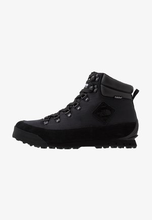 Bota de senderismo negra de altura media con suela robusta, ojales metálicos para los cordones, cuello acolchado y etiqueta impermeable HydroSeal en el lateral.