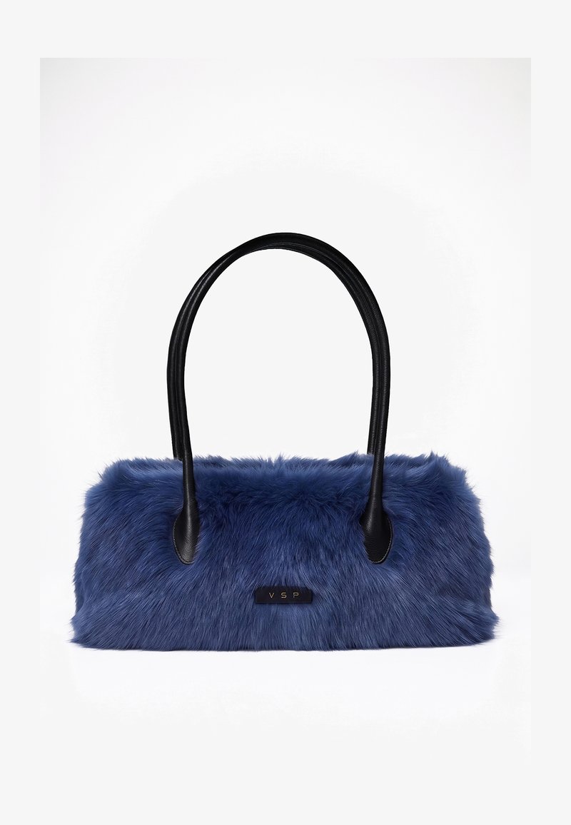 Sac à main en fausse fourrure bleue avec des poignées en cuir noir et une petite étiquette noire avec les lettres dorées VSP sur le devant.