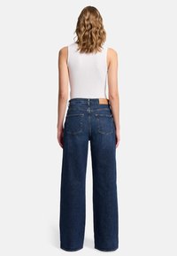 Högmidjade, vida jeans i mörkblå denim. Har en läderlapp på bakstycket av midjan och två bakfickor.