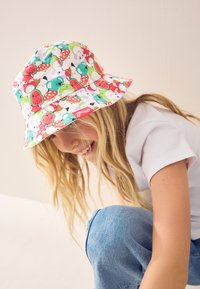 Cappello a secchiello colorato con un motivo giocoso di frutti e animali, realizzato in stoffa, con tesa larga e dettagli cuciti.