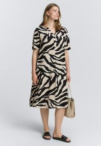 Abito a maniche corte in tessuto beige con un audace motivo a strisce zebra nere, con una vestibilità morbida e scollo a V.