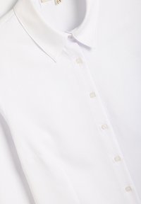 Hvid polo skjorte med tekstureret stof, med en klassisk krave og seks knapper. Glat finish med diskret syning.