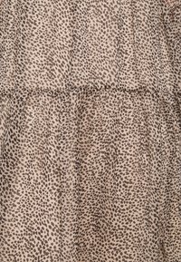 Kevyt kangas, jossa on beige pohja ja musta eläinkuos. Materiaalissa on pehmeä rakenne ja rypytetty yksityiskohta.