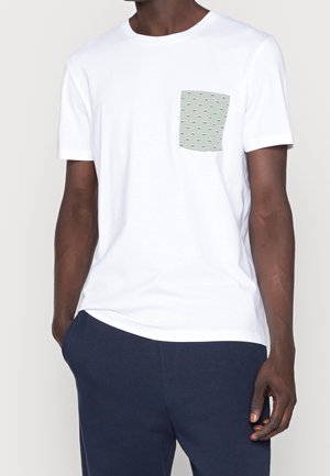 Camiseta de manga corta blanca con un bolsillo verde que presenta un patrón de pequeñas formas negras. Tela de algodón suave, diseño clásico de cuello redondo.