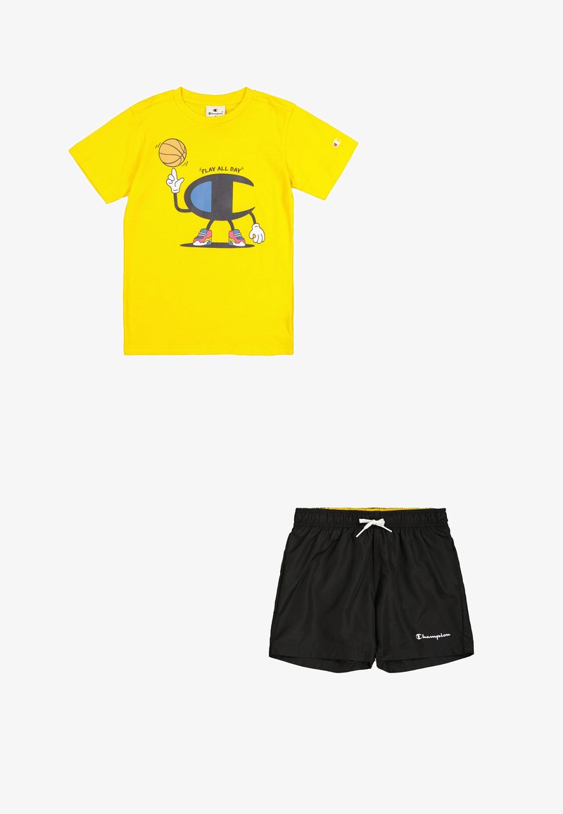 Camiseta de algodón amarilla con un gráfico de baloncesto y el texto "JUGAR TODO EL DÍA". Pantalones cortos ligeros negros con cinturilla elástica y logo de Champion.