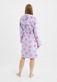 Paarse badjas met capuchon van zacht materiaal, voorzien van een all-over hartjespatroon in tinten oranje en rood, met een ceintuur in de taille en lange mouwen.