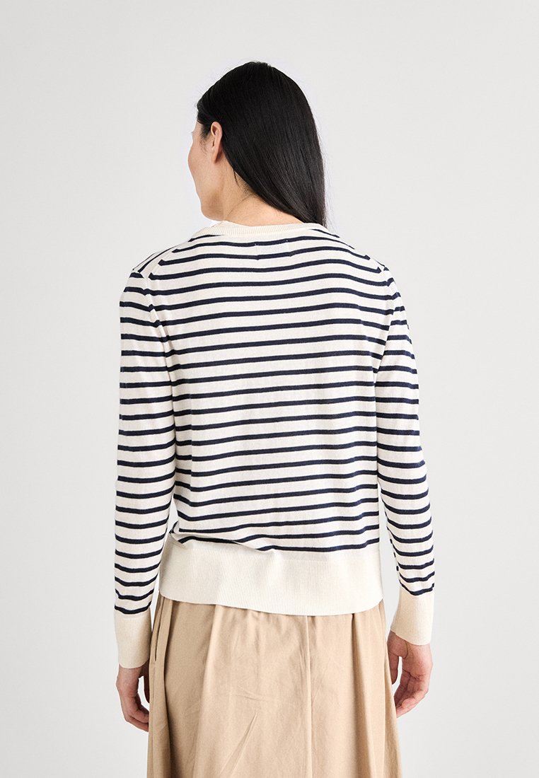 Gestreifter Pullover in Creme mit marineblauen Streifen, verfügt über einen Rundhalsausschnitt sowie gerippte Bündchen und Saum, hergestellt aus einem weichen Strickmaterial.
