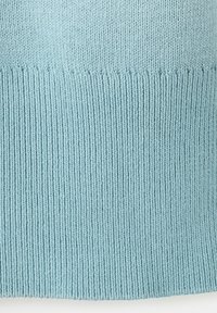 Hellblauer Strickstoff mit Rippenmuster am unteren Rand, der nach oben hin in einen glatten glatt rechten Maschen übergeht.