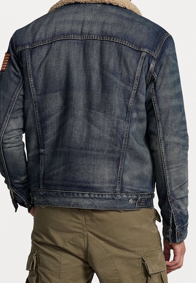 Jeansjacka med fårskinnskrage, mörkblå, normal passform, synlig sömnad och en amerikansk flagga på vänster axel.