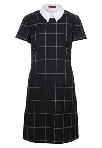 Svart klänning med korta ärmar, vit krage och vitt rutmönster. Tillverkad av ett slätt tyg med en figursydd passform och knälång design.