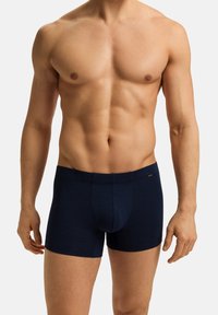 Boxer ajustados de color azul marino hechos de tejido suave, con un diseño ceñido y una bolsa contorneada. Cintura elástica sencilla con acento de logo.