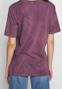 Lila bomulls-t-shirt med en avslappnad passform, korta ärmar och en urblekt textur. Baksidan har minimal sömnad och inga grafiska motiv eller logotyper.