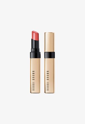 Rouge à lèvres dans un tube noir et doré. Le raisin est d'une teinte corail doux, avec une texture lisse et une pointe arrondie pour une application facile.