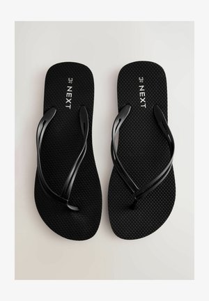 Svarta flip-flops med texturerade sulor och tunna remmar. Har "NEXT"-logotyp och storleksmarkeringar på inläggssulan. Enkel, platt design.