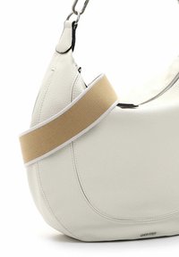 Borsa in pelle bianca con design curvo, dotata di una tracolla in tessuto beige e finiture in metallo argentato. Chiusura con zip nella parte superiore.