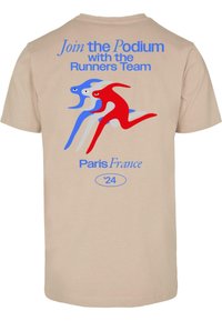 Beige tričko s třemi abstraktními běžeckými postavami v červené a modré. Text zní "Připojte se k pódiu s týmem běžců Paříž Francie '24."