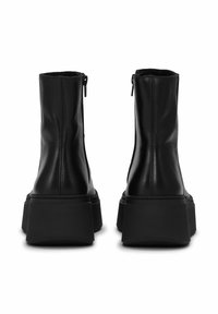 Crne kožne gležnjače s masivnim crnim potplatom, sa bočnim patentnim zatvaračem, bešavnom završnom obradom i glatkom teksturom.