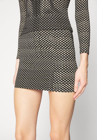 Zwarte mesh-jurk met lange mouwen en een getailleerde silhouet. Heeft grote crèmekleurige stippen en een korte zoom.