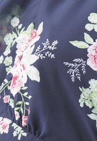 Marineblått stoff med blomsterdesign i nyanser av rosa og grønn. Myk tekstur med samlet detaljer, som viser detaljert bladverk og blomster.