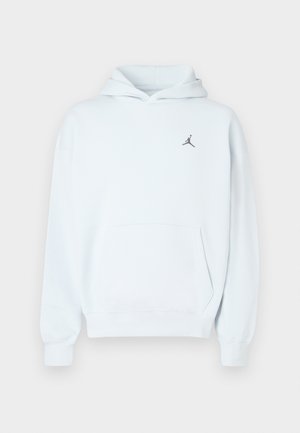 Hanorac albastru deschis din material moale, cu buzunar tip cangur, glugă cu șnur și un mic logo negru Jumpman pe piept.