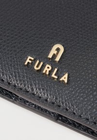 Black textured leather wallet featuring a gold "FURLA" logo, with visible stitching and a smooth finish on edges.
